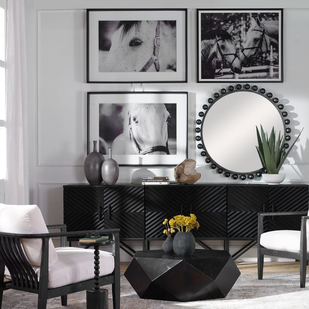 Modern living room with black and white decor, including a console table, chairs, and wall art.