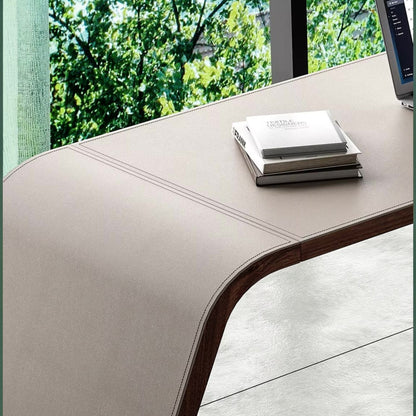 Urban Ashram Arden executive desk in light saddle leather with curved edges and visible stitching in a bright office.