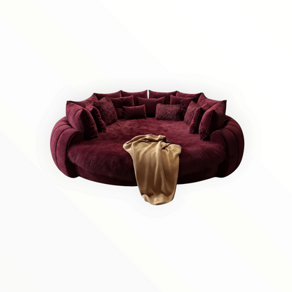 Urban Ashram Dream Lounger round movie bed in deep burgundy velvet with plush faux fur and a draped beige throw.
