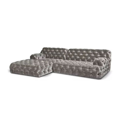 Urban Ashram Coco Miralda smoke grey velvet Chesterfield sectional sofa with deep button tufting on a white background