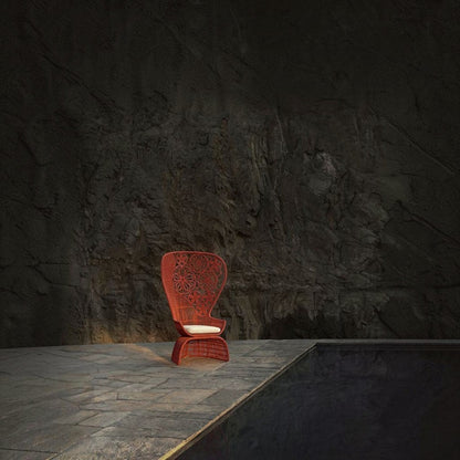 Urban Ashram Genevieve armchair with red woven floral high-back and white seat cushion on a stone patio by a pool.