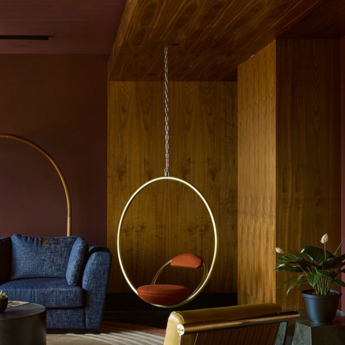 Urban Ashram Hanging Hoop Chair by Lee Broom featuring a brushed brass circular frame and red Kvadrat wool upholstery.