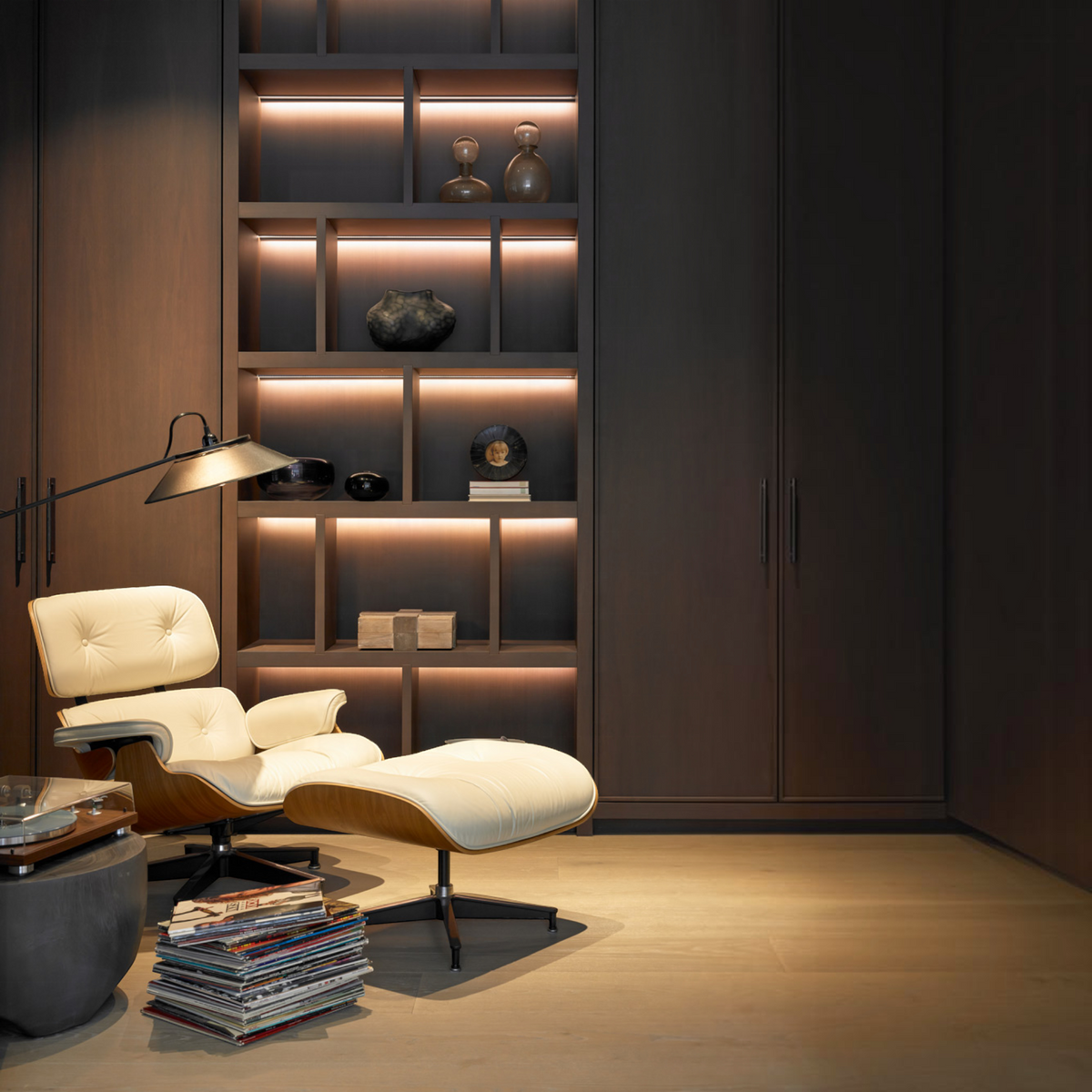 Urban Ashram mid-century lounge chair and ottoman with cream leather upholstery and wood frame in a modern library.