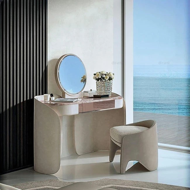 Urban Ashram Aveline vanity set with pink-veined marble top, curved base, and matching upholstered stool by the sea.