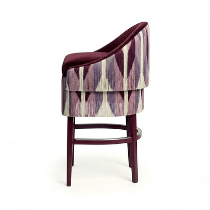 Urban Ashram Atelier Fringe Bar Stool with a plum velvet seat and geometric patterned fringe skirt on a wooden frame.