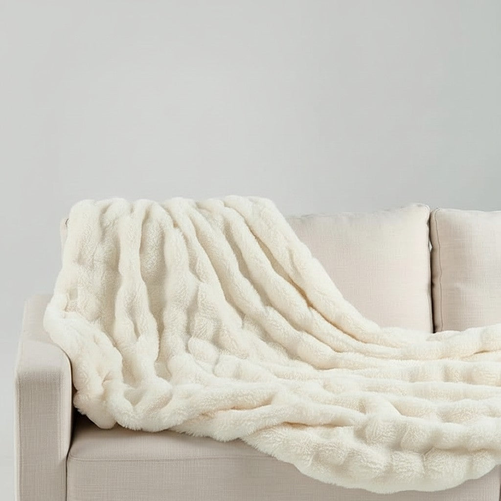 Urban Ashram Plushie LUXE cream faux fur throw blanket draped over a neutral sofa for a cozy home aesthetic.