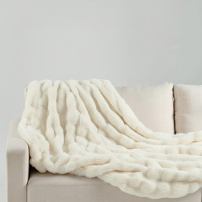 Urban Ashram Plushie LUXE cream faux fur throw blanket draped over a neutral sofa for a cozy home aesthetic.