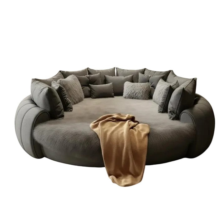 Urban Ashram Dream Lounger round movie bed in grey with plush cushions and a soft tan throw blanket.