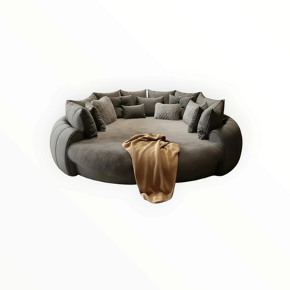 Urban Ashram Dream Lounger round movie bed in grey with plush cushions and a soft tan throw blanket.