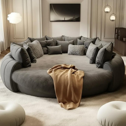 Urban Ashram Dream Lounger round movie bed in charcoal grey with plush cushions and a tan throw blanket.