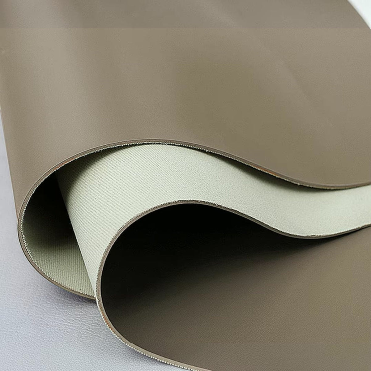 Urban Ashram Arden saddle leather material swatch showing smooth brown leather surface and light beige backing