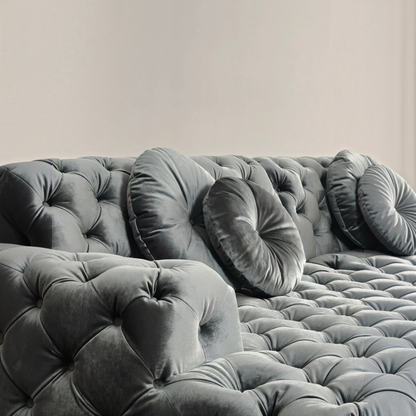 Urban Ashram Coco Miralda Chesterfield sofa in smoke grey velvet with deep button tufting and round accent pillows.