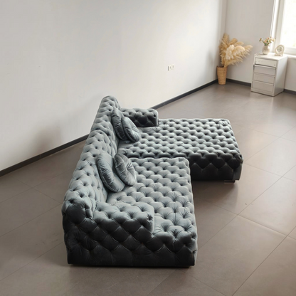 Urban Ashram Coco Miralda smoke grey velvet Chesterfield sectional sofa with deep button tufting and round cushions.